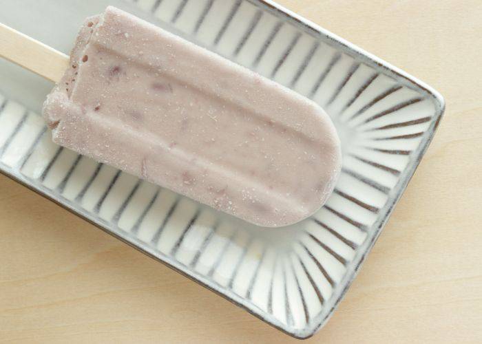 A red bean ice cream on a serving dish. Beneath the ice cream you can see the darker red beans within.